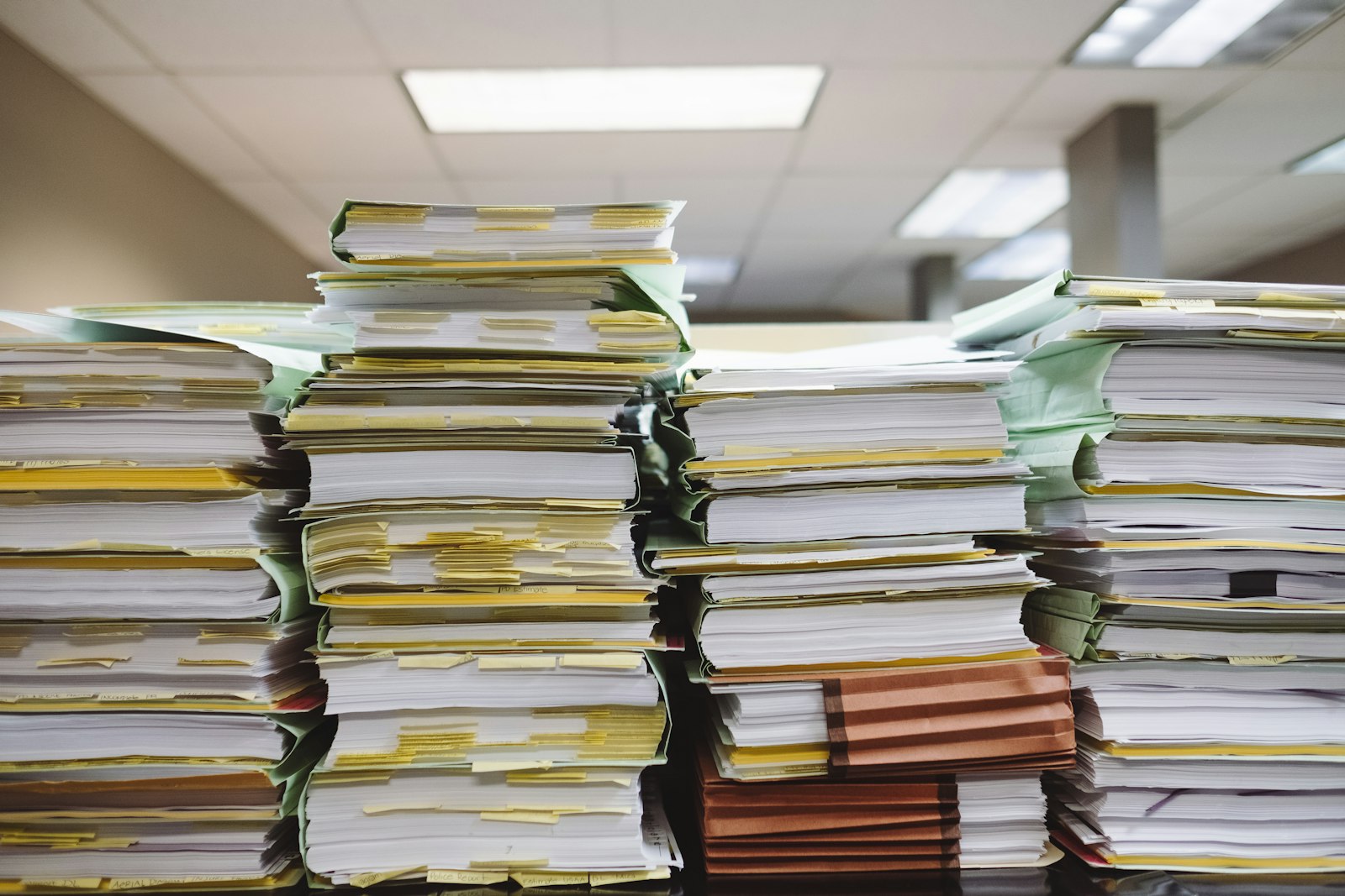 Stacks of client files and folders piled on an office desk